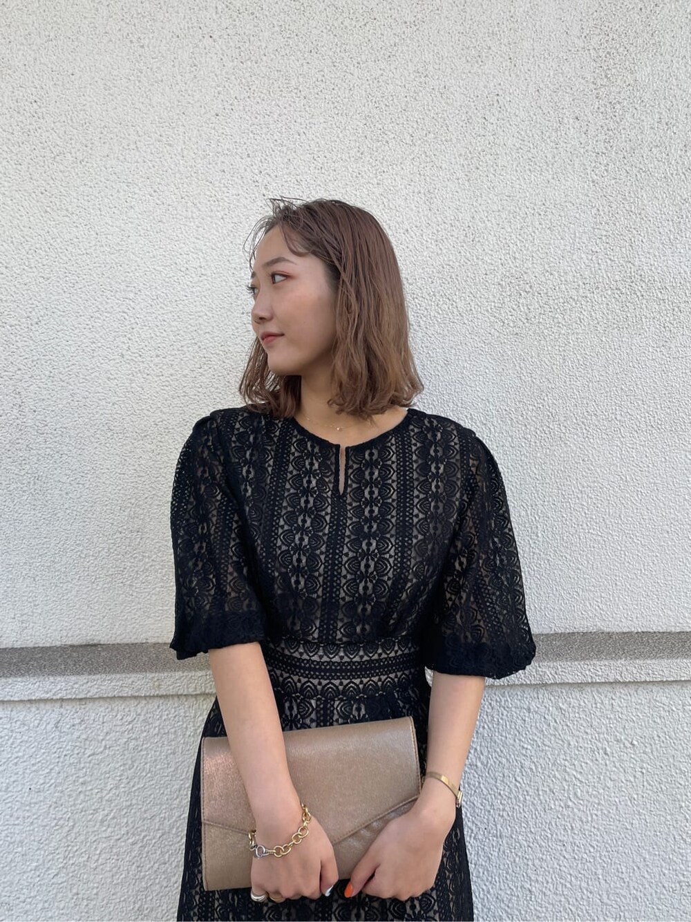 ゴールド系のパンプス、ゴールド系のクラッチバッグ、ブラック系のドレスを着用したレディースの冬コーディネートの4枚目の写真