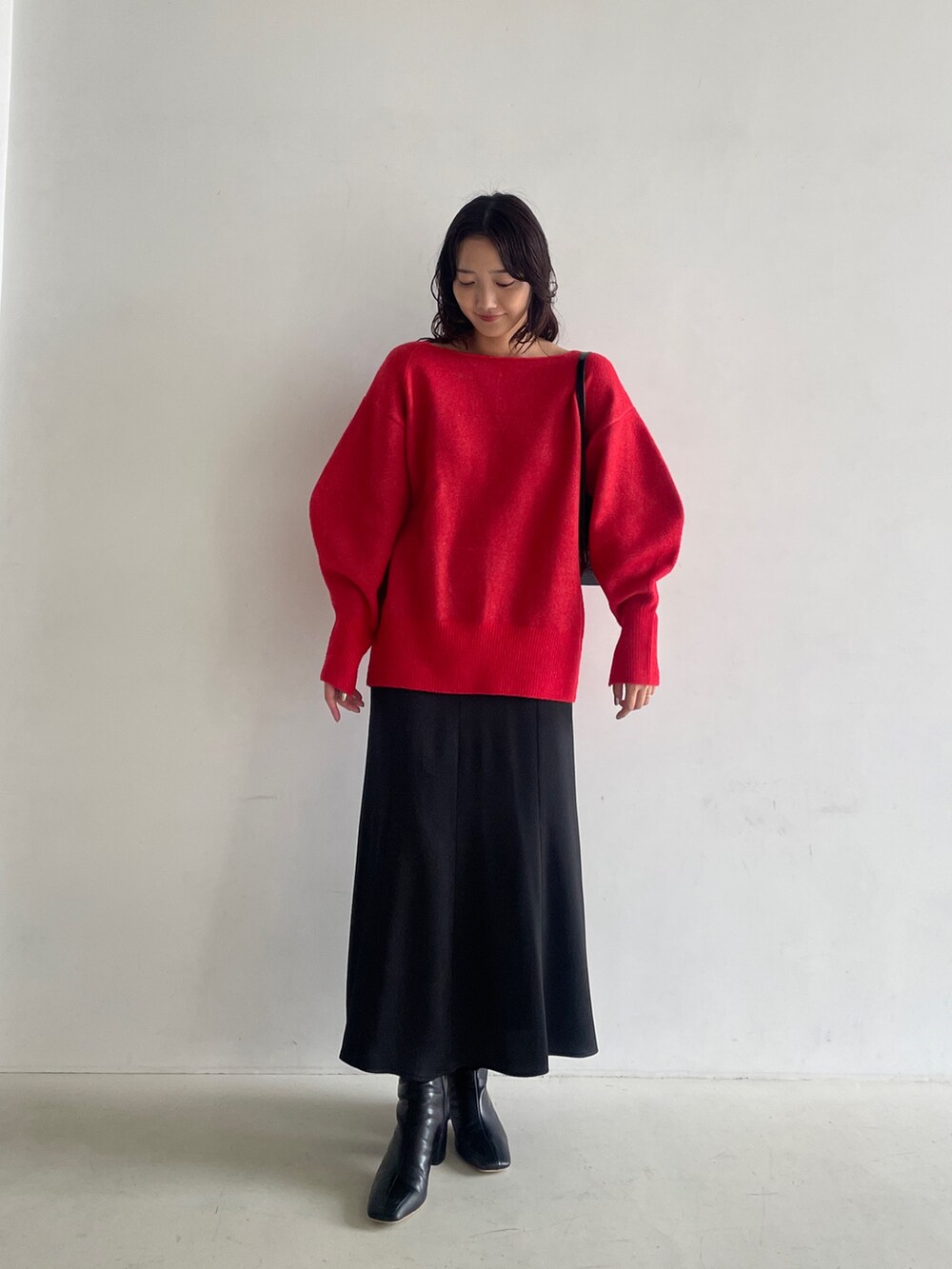 ブラック系のブーツ、ブラック系のスカート、レッド系のニット/セーターを着用したレディースの秋コーディネートの5枚目の写真