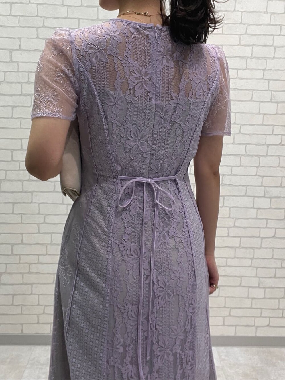 ベージュ系のパンプス、パープル系のドレス、ゴールド系のネックレスを着用したレディースの春コーディネートの6枚目の写真