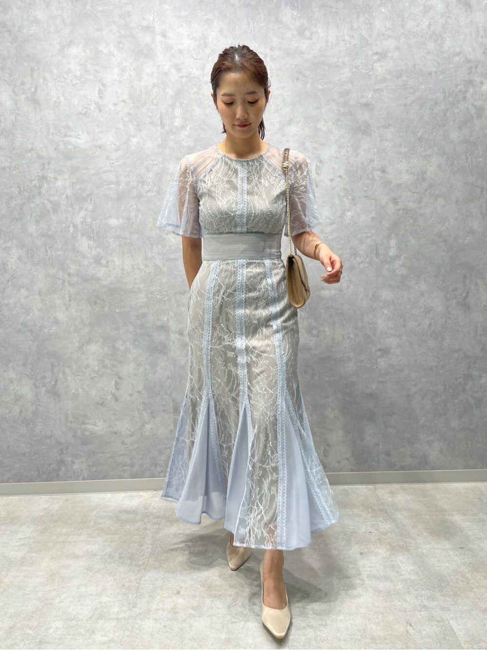 ゴールド系のクラッチバッグ、ベージュ系のパンプス、ブルー系のドレスを着用したレディースの春コーディネートの2枚目の写真