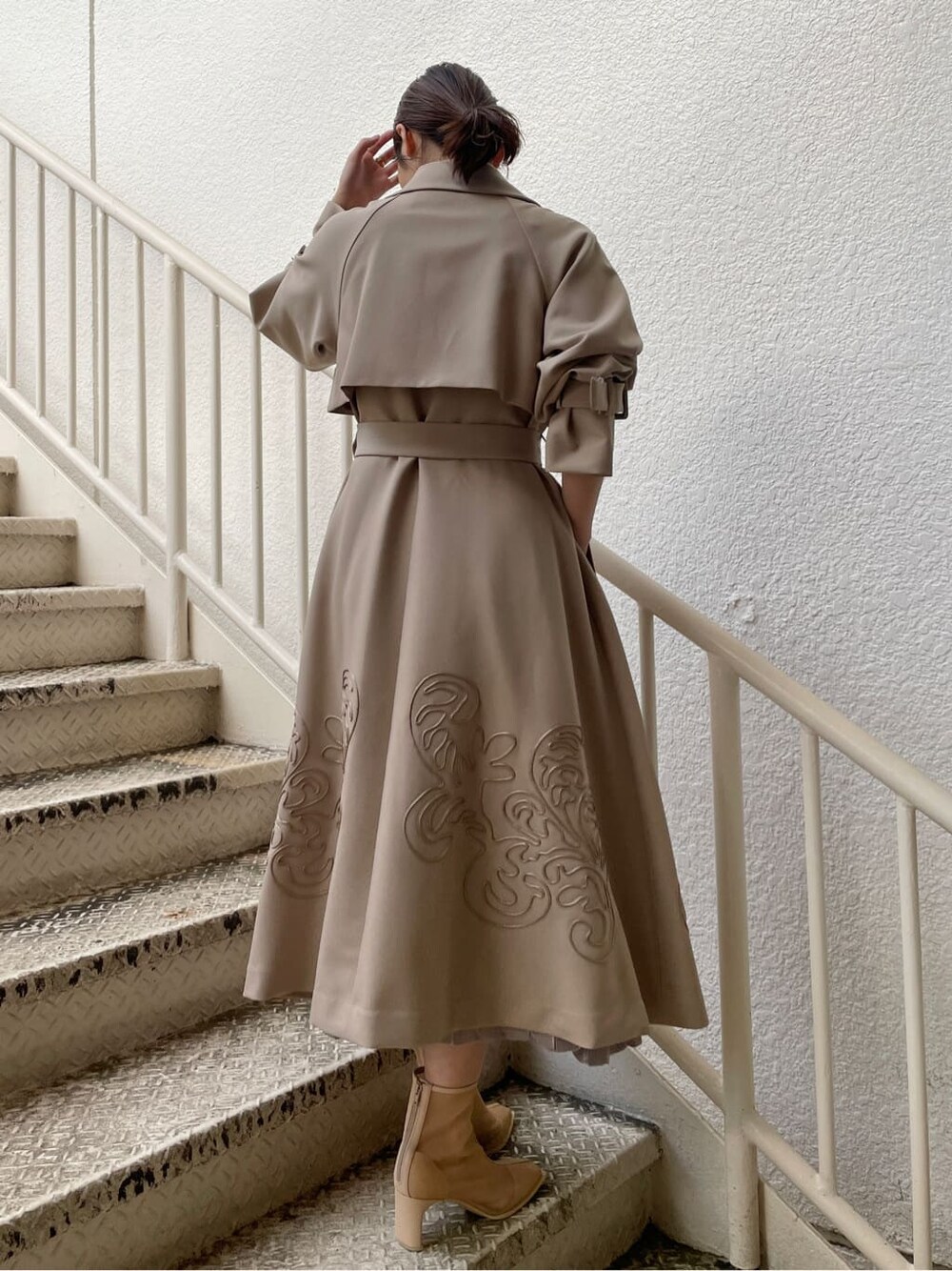 ベージュ系のトレンチコート、グレー系のワンピース、ベージュ系のブーツを着用したレディースの春コーディネートの4枚目の写真