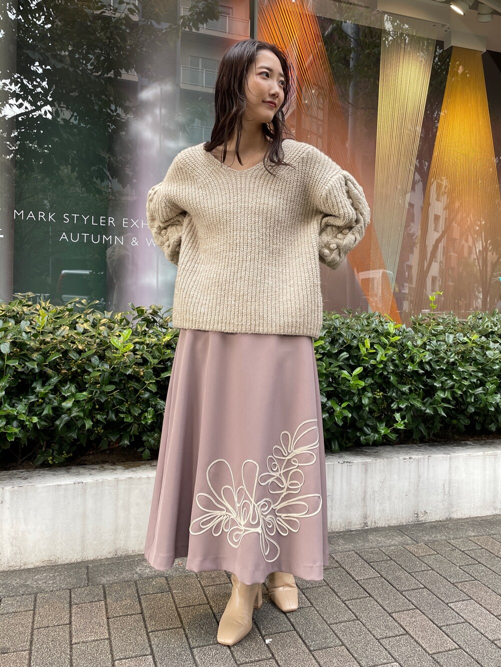 ホワイト系のニット/セーター、ホワイト系のその他アウター、ベージュ系のスカートを着用したレディースの秋コーディネートの4枚目の写真