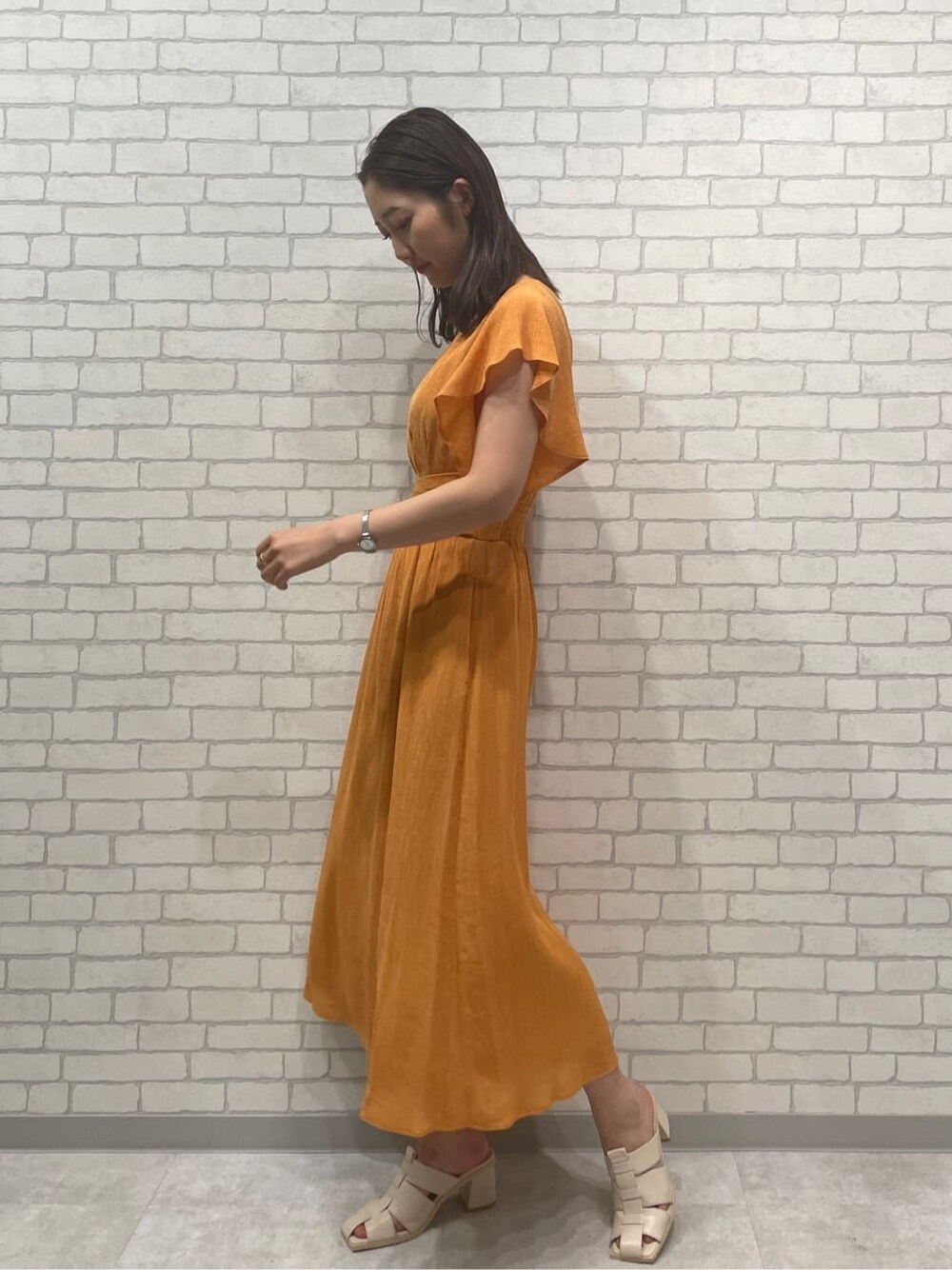オレンジ系のワンピース、ホワイト系のサンダルを着用したレディースの春コーディネートの5枚目の写真