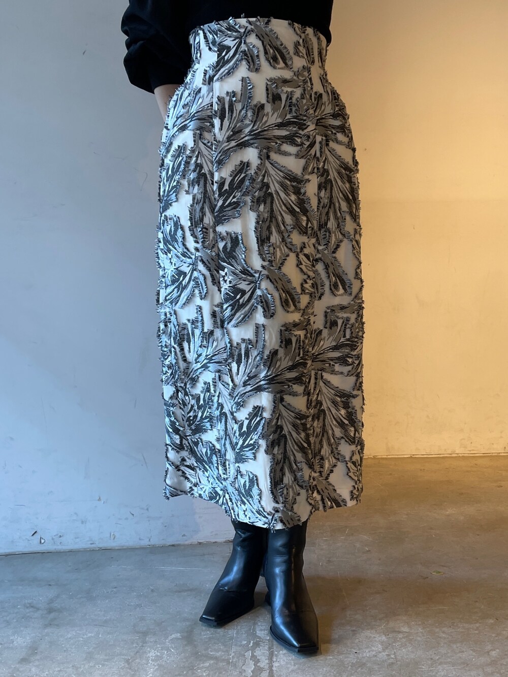 ブラック系のスカート、ブラック系のニット/セーター、ブラック系のブーツを着用したレディースの冬コーディネートの8枚目の写真