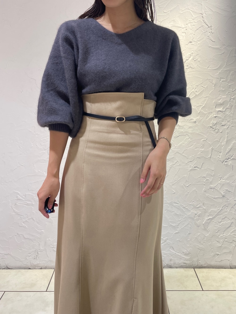 グレー系のニット/セーター、ベージュ系のスカート、ブラック系のブーツを着用したレディースの秋コーディネートの6枚目の写真