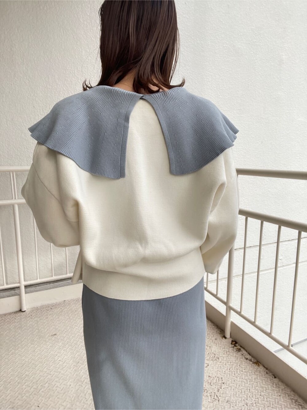 ブルー系のワンピース、ブラック系のハンドバッグ、ホワイト系のパンプスを着用したレディースの冬コーディネートの3枚目の写真