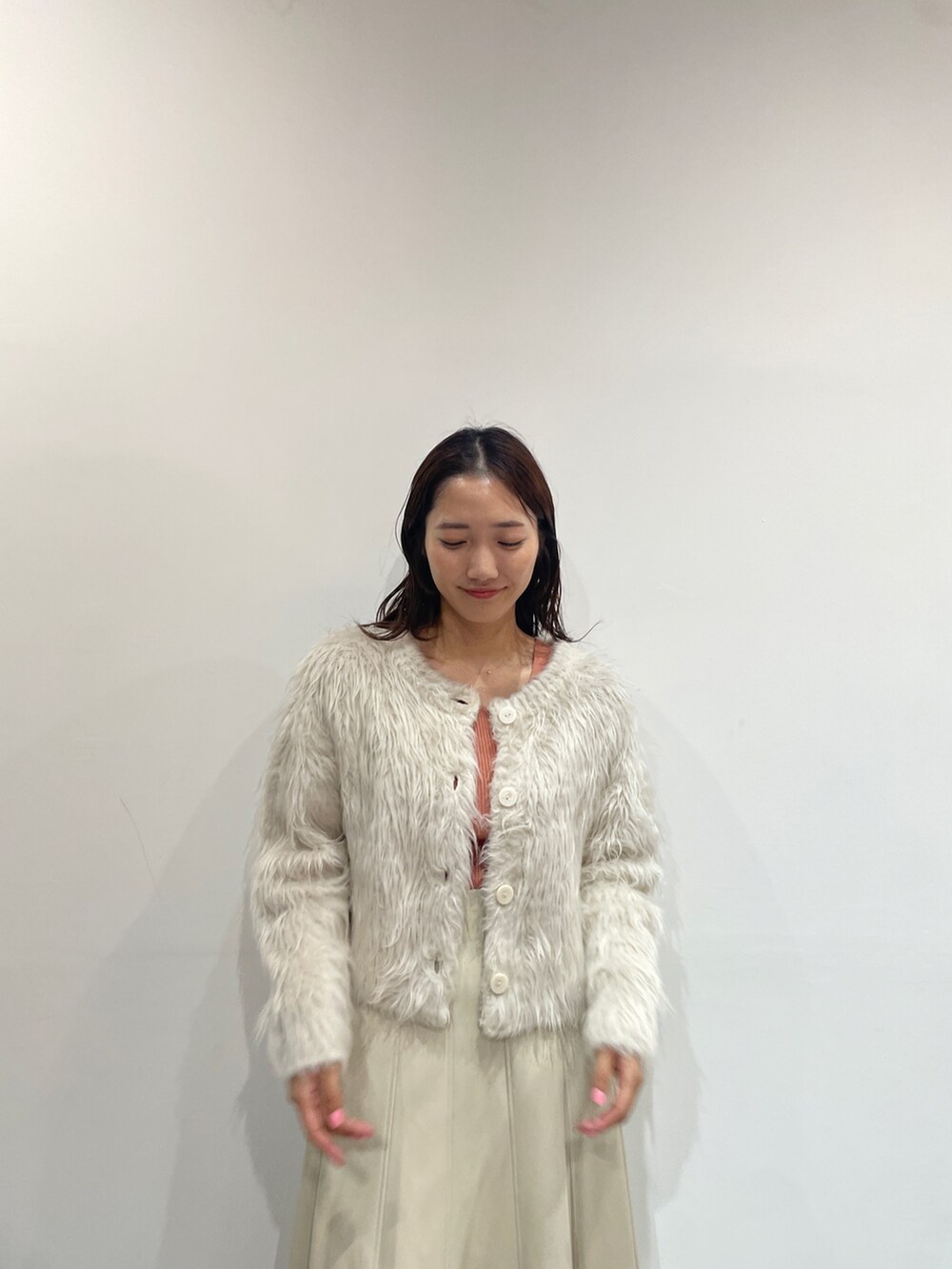 ホワイト系のスカート、ベージュ系のブーツ、オレンジ系のニット/セーターを着用したレディースの夏コーディネートの6枚目の写真