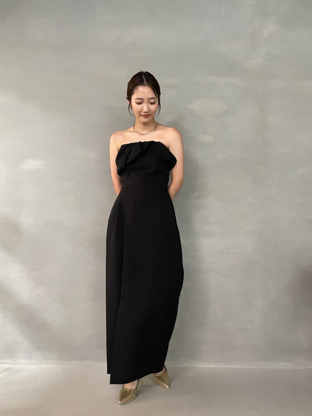 ゴールド系のパンプス、ブラック系のパンツドレス、シルバー系のチョーカーを着用したレディースの夏コーディネートの2枚目の写真