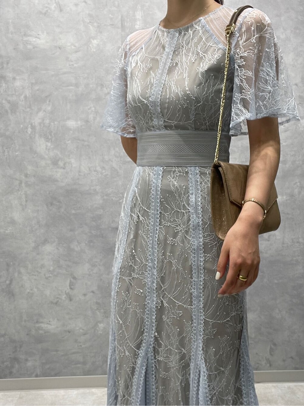 ゴールド系のクラッチバッグ、ベージュ系のパンプス、ブルー系のドレスを着用したレディースの春コーディネートの6枚目の写真