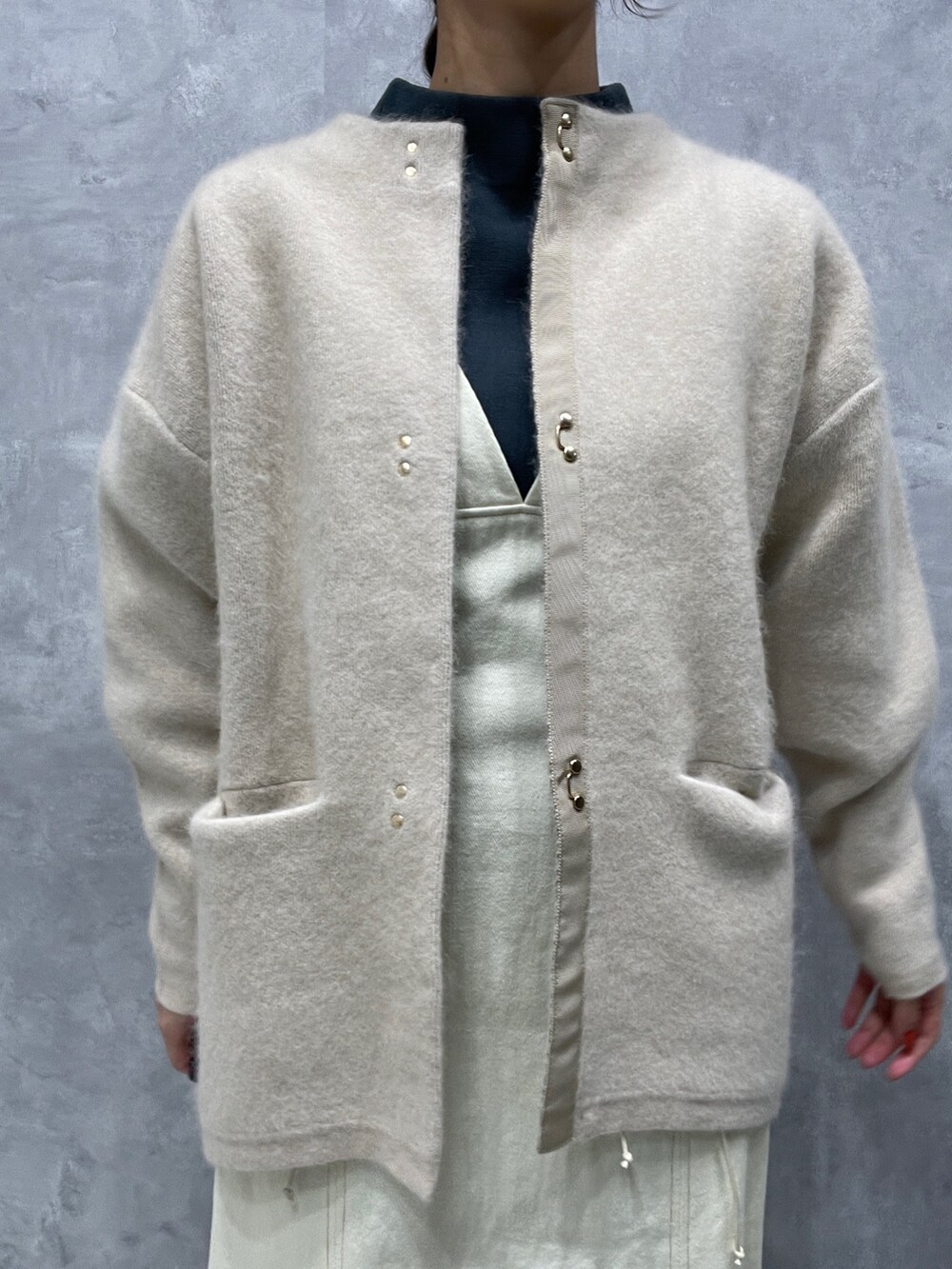 グリーン系のニット/セーター、ホワイト系のカーディガン/ボレロ、ブラック系のブーツを着用したレディースの冬コーディネートの8枚目の写真