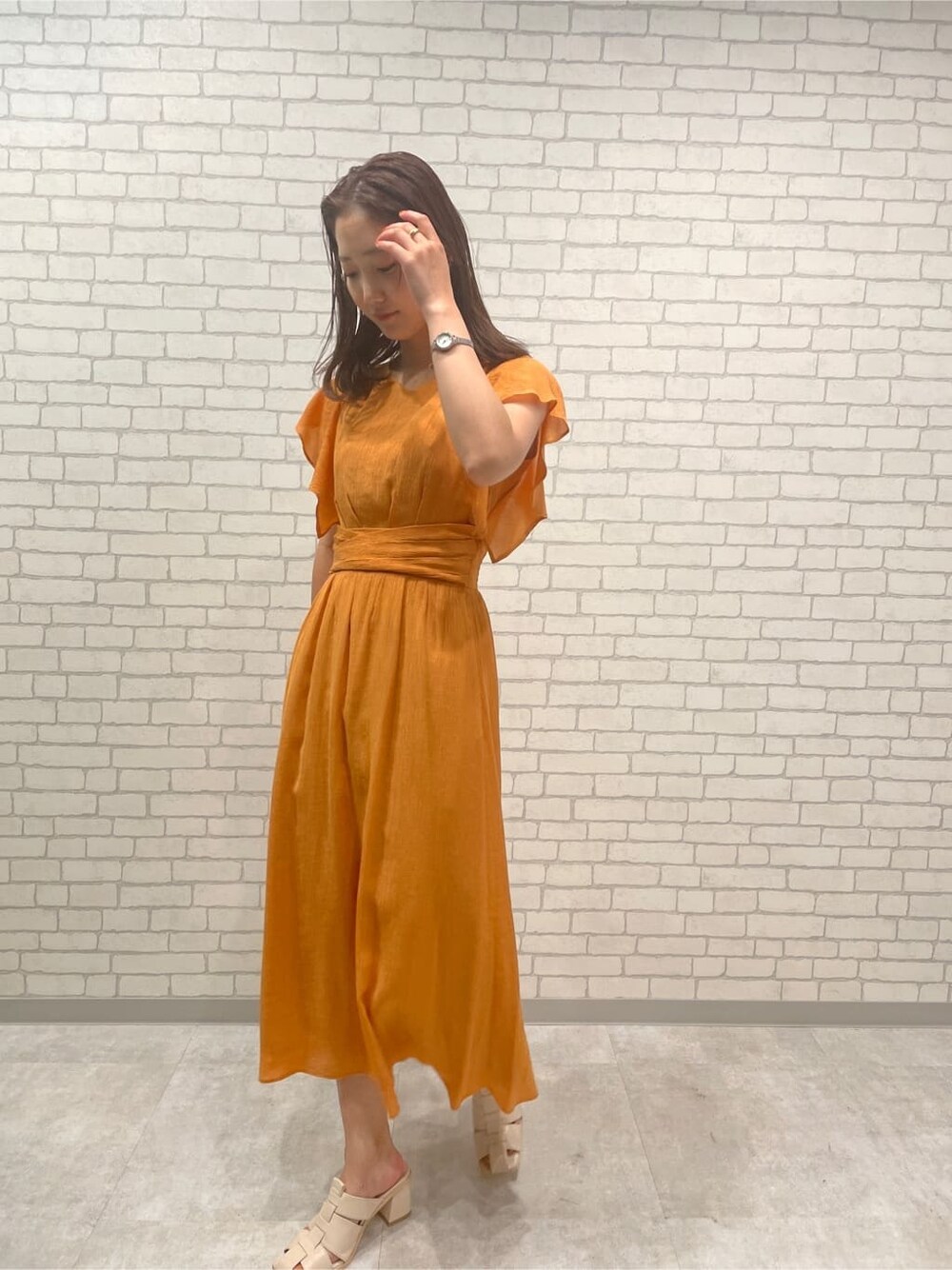 オレンジ系のワンピース、ホワイト系のサンダルを着用したレディースの春コーディネートの3枚目の写真