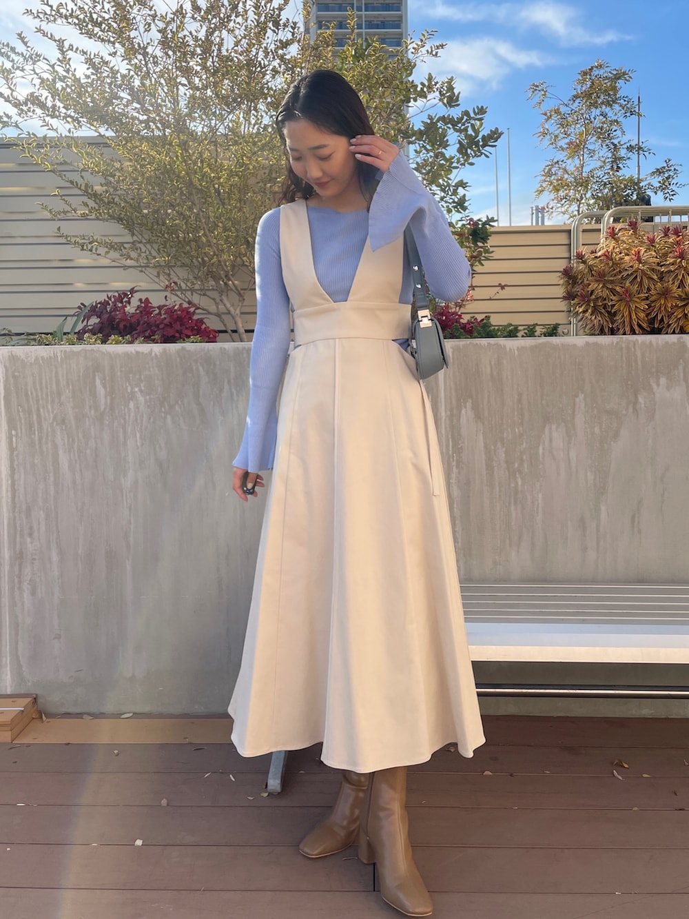 ブルー系のニット/セーター、ベージュ系のブーツ、ホワイト系のジャンパースカートを着用したレディースの冬コーディネートの3枚目の写真