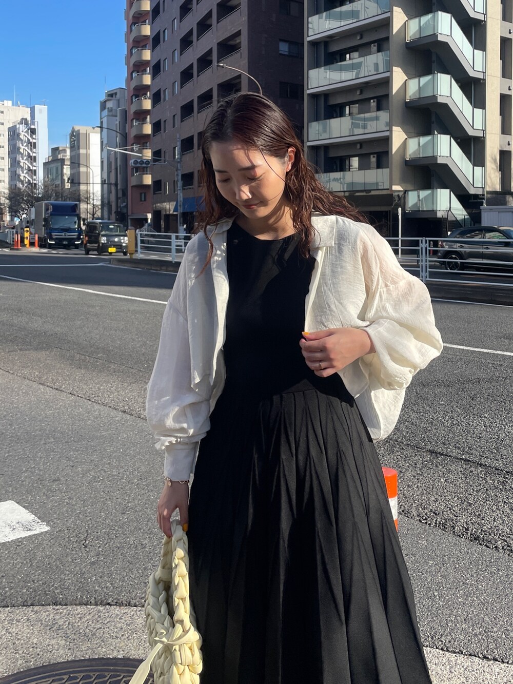 ブラック系のワンピース、ベージュ系のハンドバッグ、ブラック系のサンダルを着用したレディースの春コーディネートの8枚目の写真