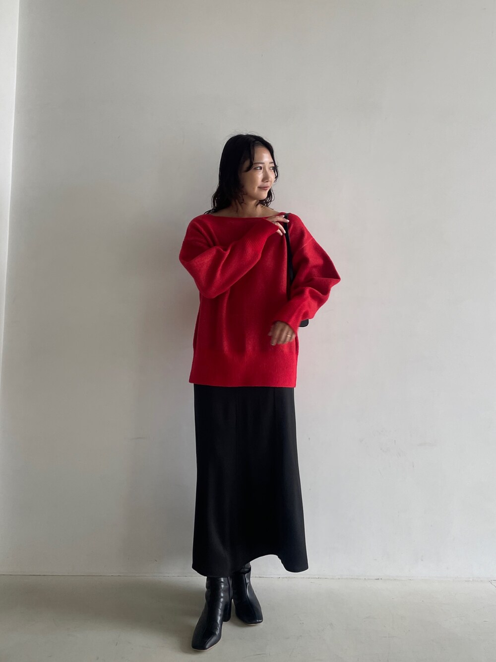 ブラック系のブーツ、ブラック系のスカート、レッド系のニット/セーターを着用したレディースの秋コーディネートの4枚目の写真