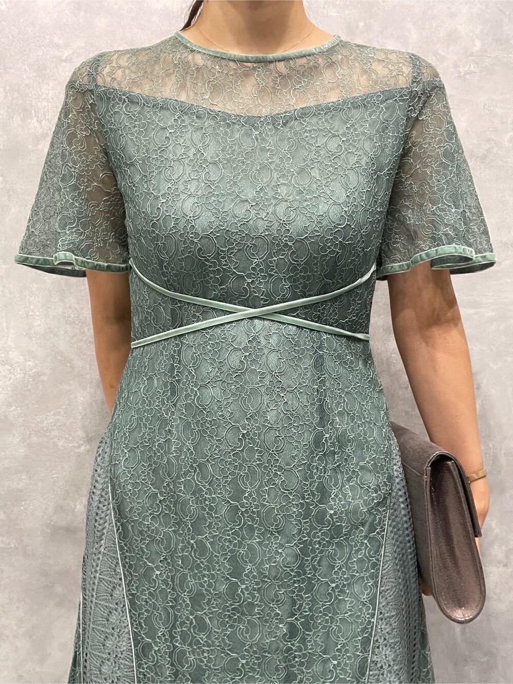 シルバー系のパンプス、シルバー系のクラッチバッグ、グリーン系のドレスを着用したレディースの夏コーディネートの7枚目の写真