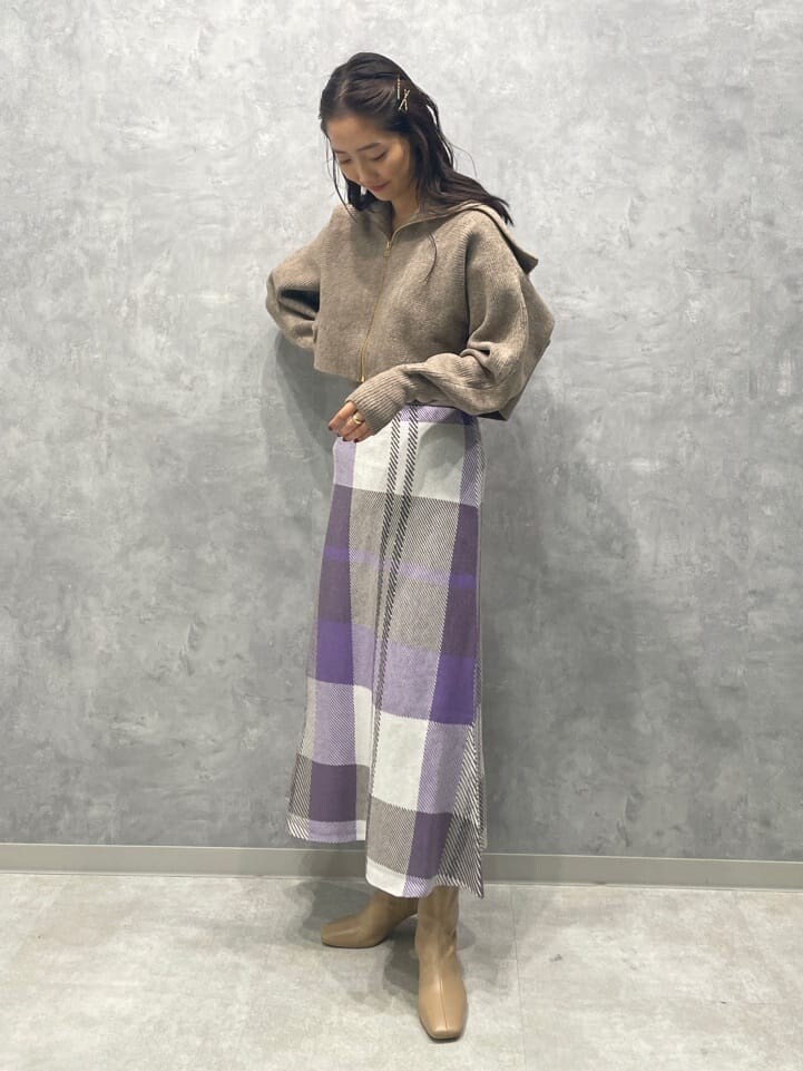 ベージュ系のブーツ、ベージュ系のカーディガン/ボレロ、パープル系のスカートを着用したレディースの秋コーディネートの2枚目の写真