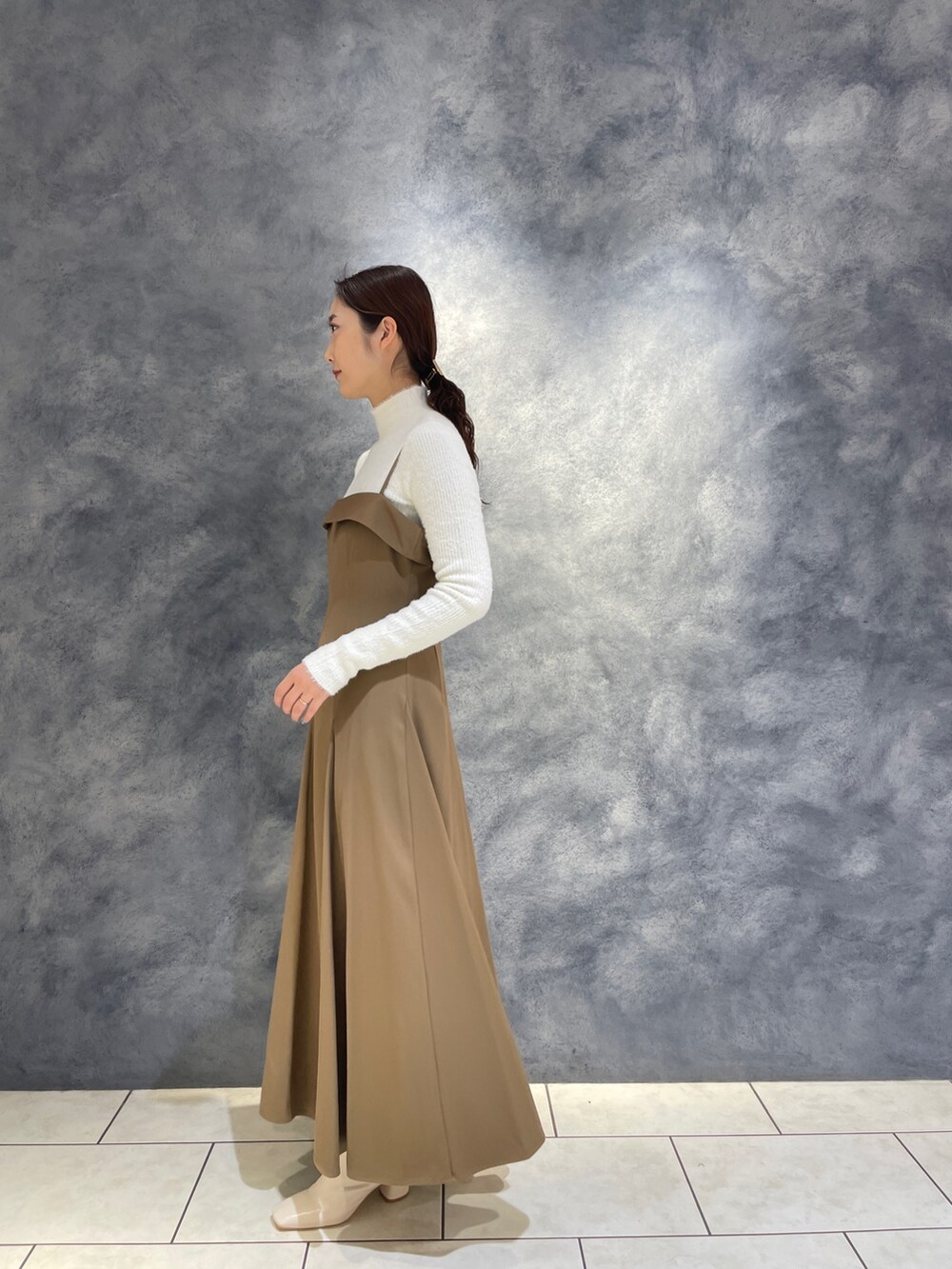 ベージュ系のワンピース、ホワイト系のニット/セーター、ホワイト系のブーツを着用したレディースの冬コーディネートの6枚目の写真