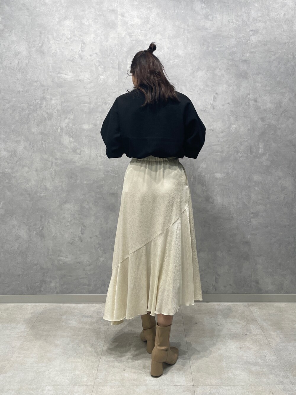 ブラック系のニット/セーター、ホワイト系のスカート、ベージュ系のブーツを着用したレディースの冬コーディネートの6枚目の写真