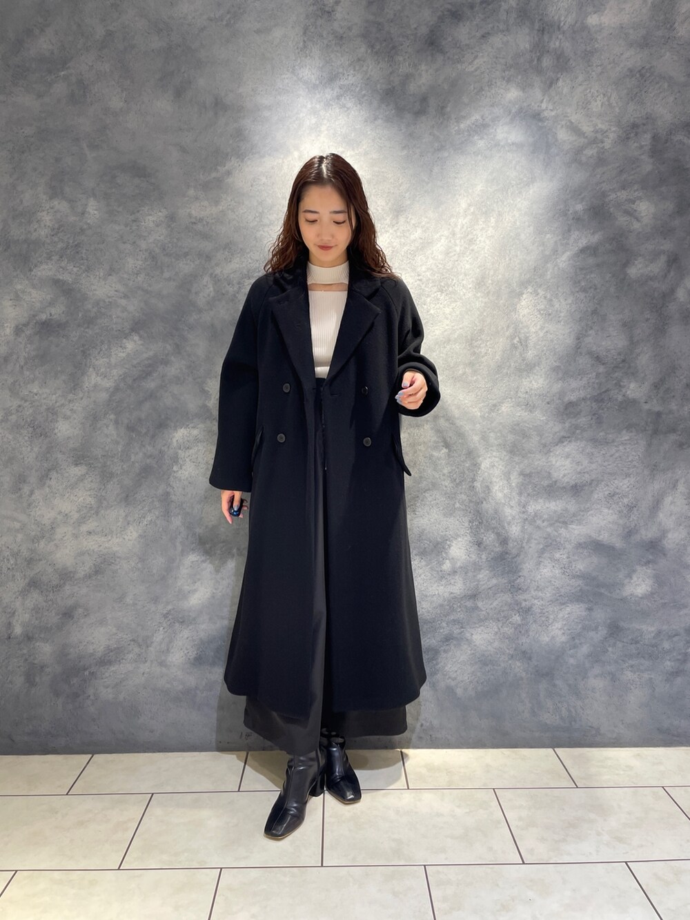 ブラック系のスカート、ホワイト系のニット/セーター、ブラック系のブーツを着用したレディースの秋コーディネートの9枚目の写真