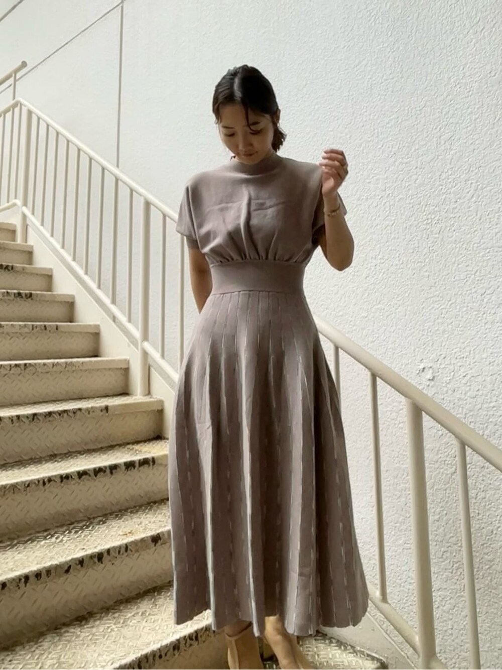 ベージュ系のトレンチコート、グレー系のワンピース、ベージュ系のブーツを着用したレディースの春コーディネートの7枚目の写真