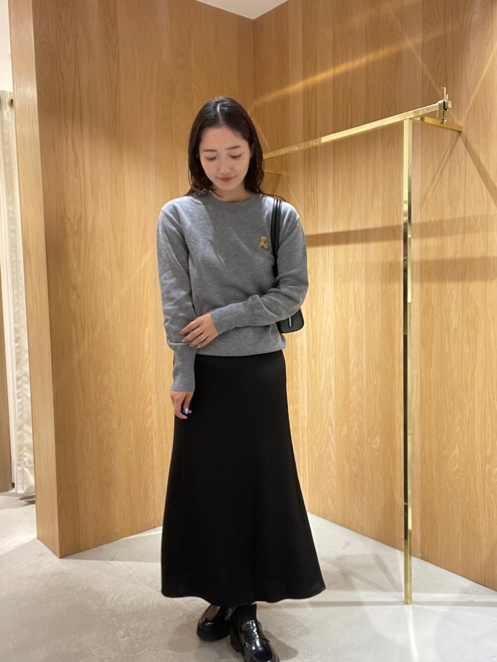 グレー系のニット/セーター、ブラック系のスカート、ブラック系のローファーを着用したレディースの秋コーディネートの4枚目の写真