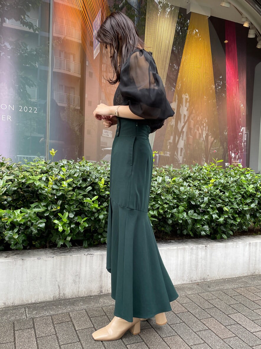 ベージュ系のトレンチコート、グリーン系のスカート、ベージュ系のトレンチコートを着用したレディースの秋コーディネートの6枚目の写真