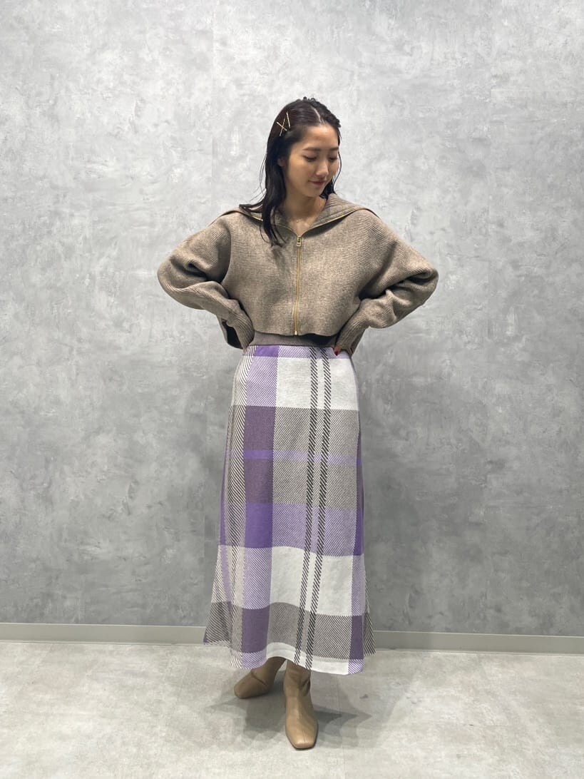 ベージュ系のブーツ、ベージュ系のカーディガン/ボレロ、パープル系のスカートを着用したレディースの秋コーディネートの3枚目の写真