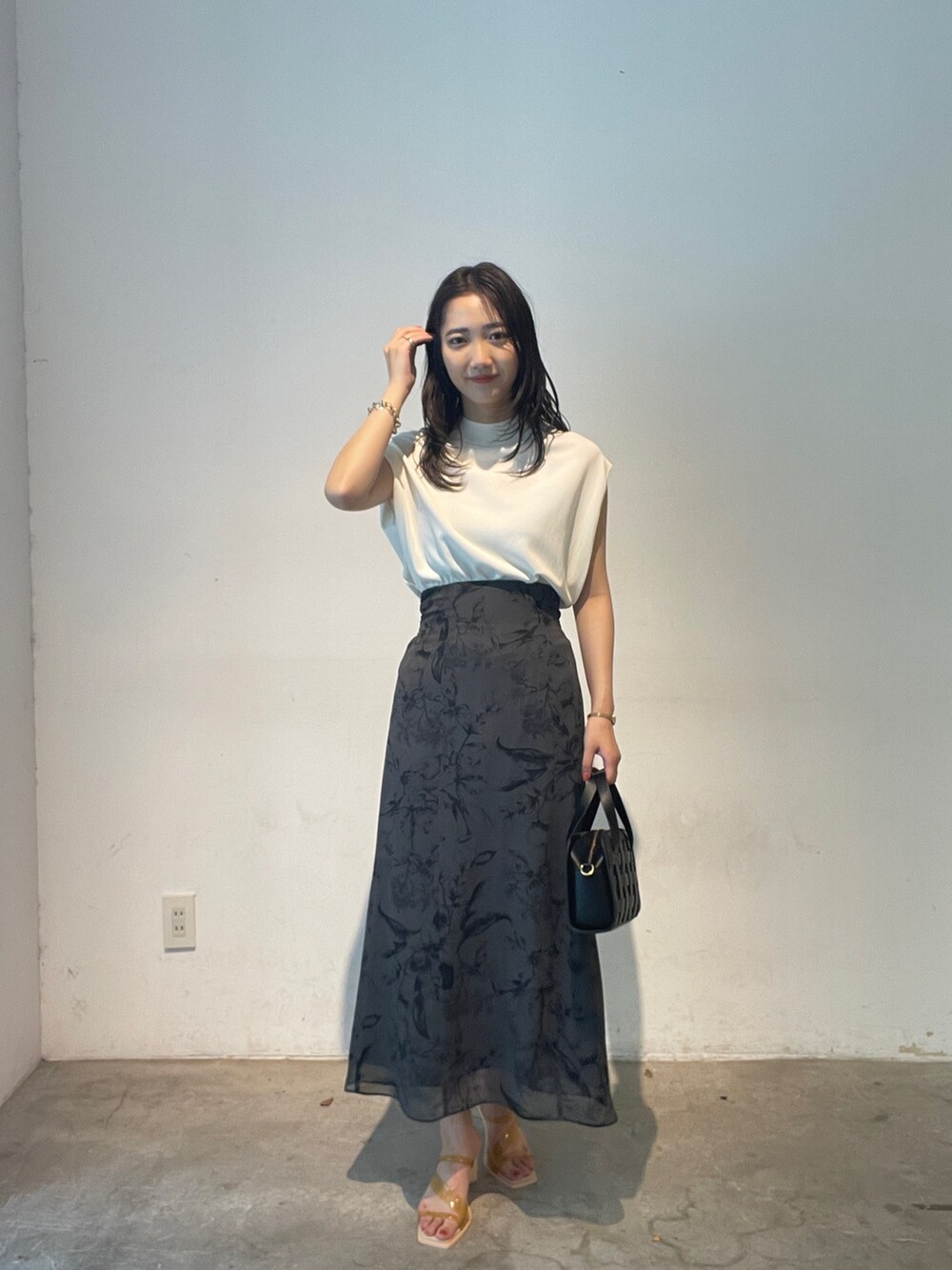 ホワイト系のニット/セーター、ブラック系のショルダーバッグ、イエロー系のサンダルを着用したレディースの夏コーディネートの6枚目の写真