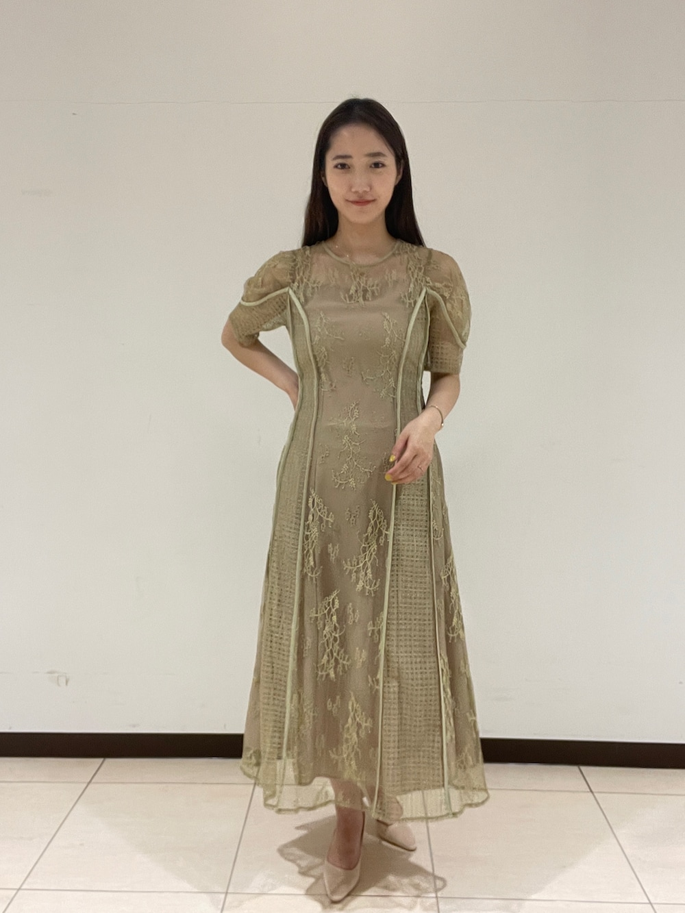 ベージュ系のパンプス、グリーン系のドレスを着用したレディースの春コーディネートの2枚目の写真