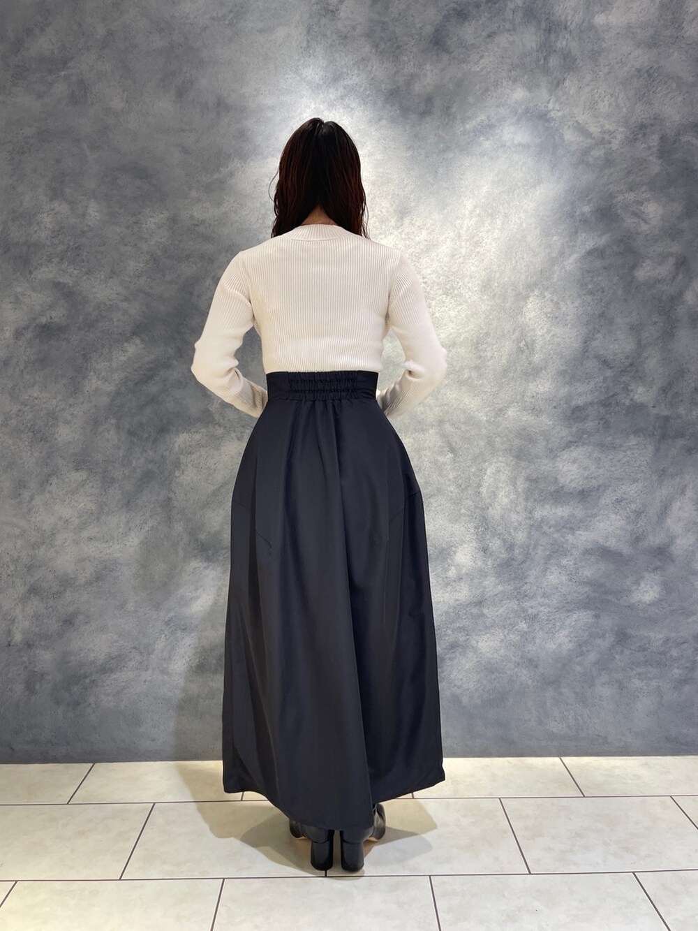 ブラック系のスカート、ホワイト系のニット/セーター、ブラック系のブーツを着用したレディースの秋コーディネートの6枚目の写真