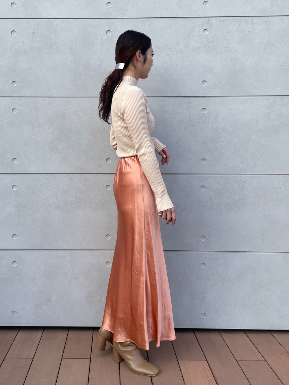 ホワイト系のニット/セーター、オレンジ系のスカート、ベージュ系のブーツを着用したレディースの冬コーディネートの5枚目の写真