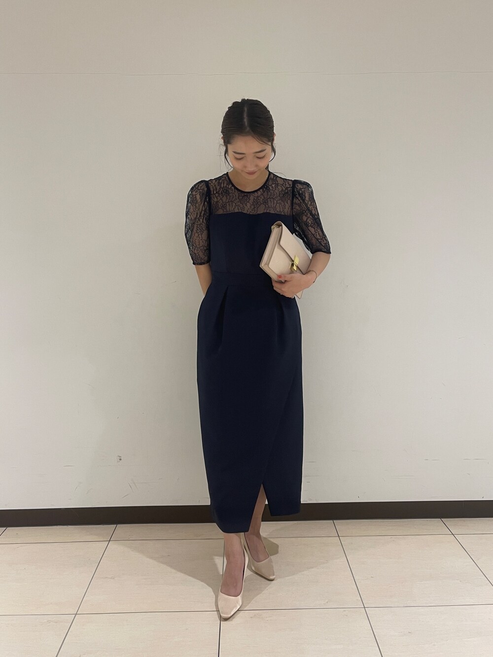 ゴールド系のクラッチバッグ、ベージュ系のパンプス、ブルー系のドレスを着用したレディースの春コーディネートの3枚目の写真