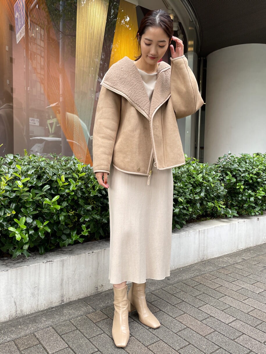 ベージュ系のブーツ、ブラウン系のブルゾン、ホワイト系のワンピースを着用したレディースの秋コーディネートの2枚目の写真