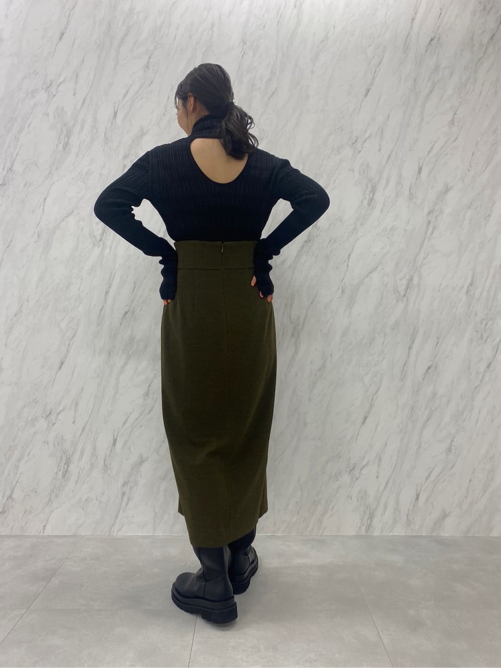 ベージュ系のスカート、ブラック系のニット/セーター、ブラック系のブーツを着用したレディースの夏コーディネートの6枚目の写真