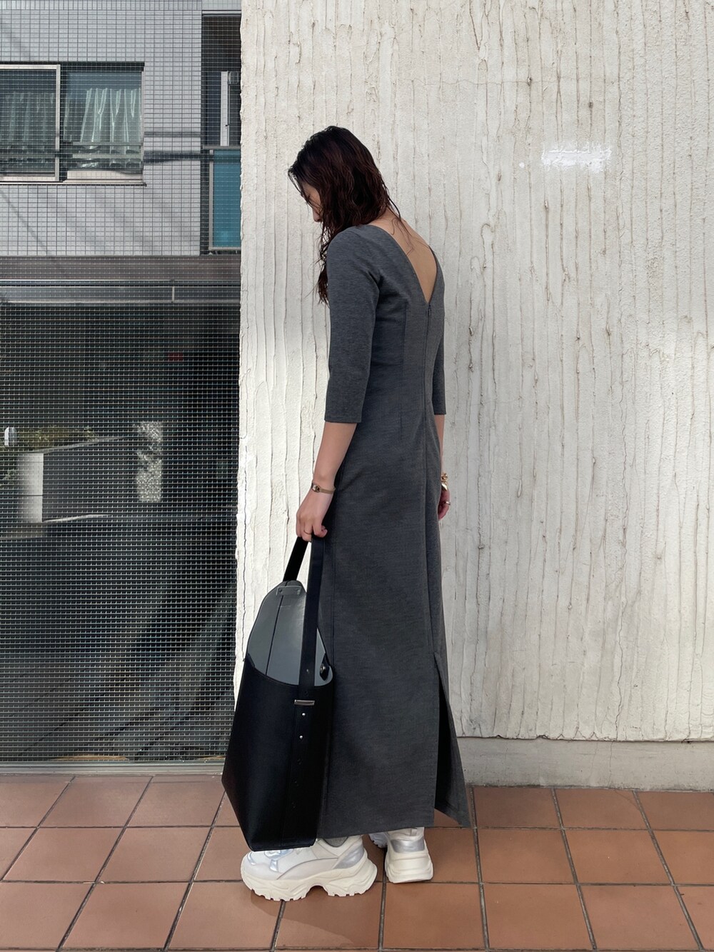 ブラック系のショルダーバッグ、グレー系のワンピース、ホワイト系のスニーカーを着用したレディースの冬コーディネートの8枚目の写真