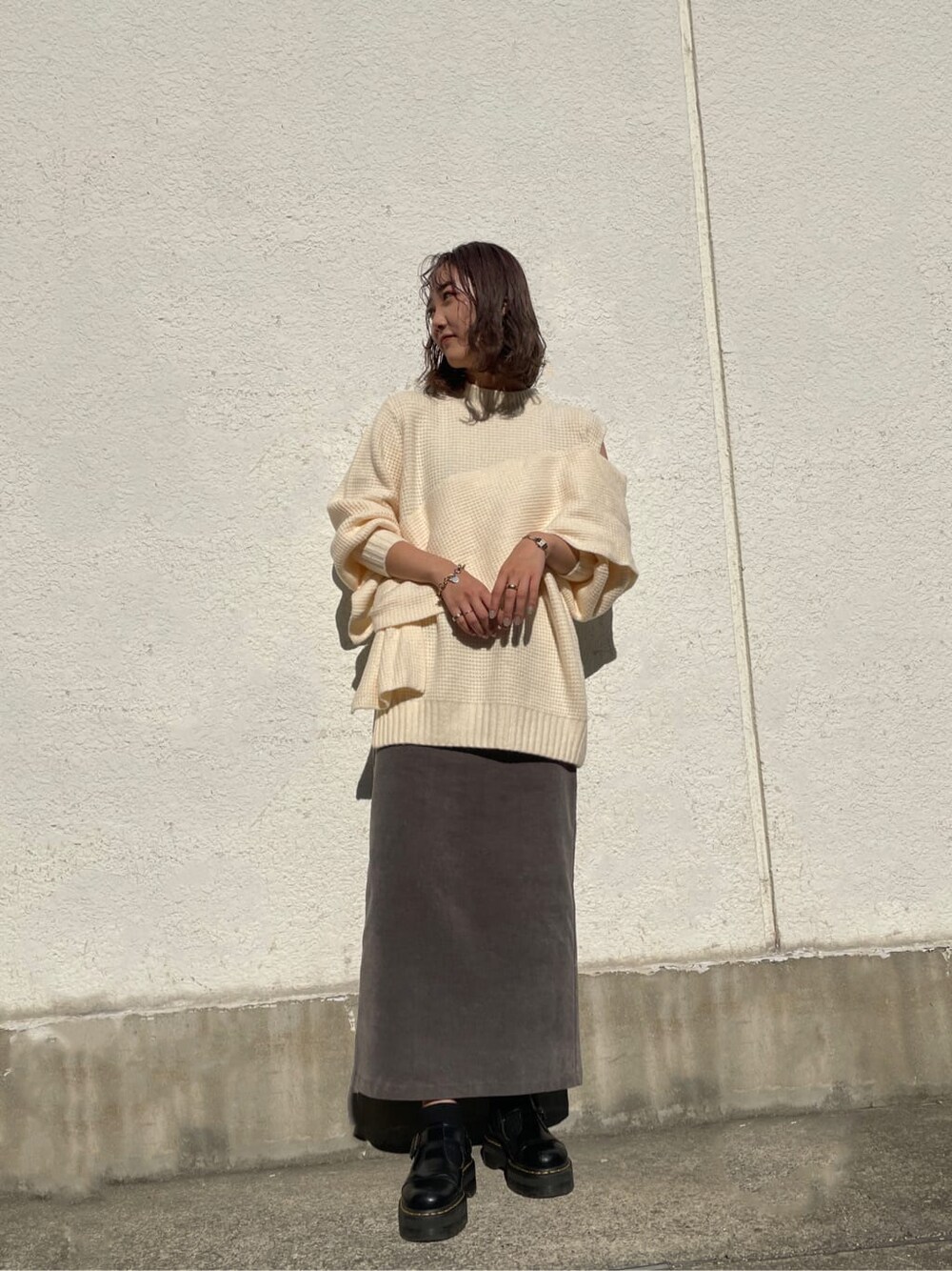 グレー系のスカート、ホワイト系のニット/セーターを着用したレディースの冬コーディネートの2枚目の写真