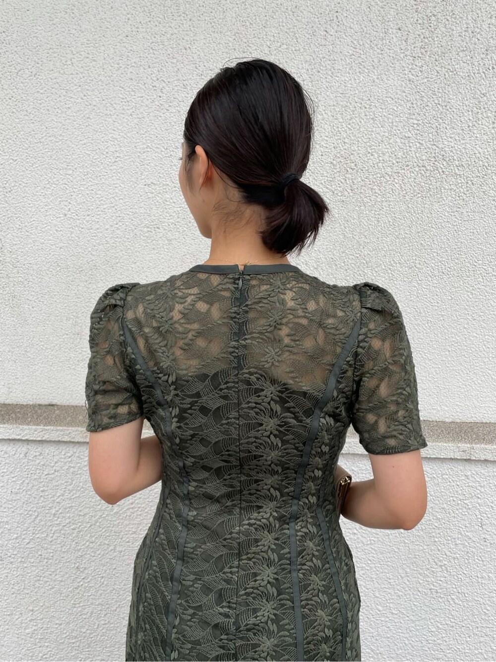 グリーン系のドレス、ベージュ系のパンプス、ブラウン系のクラッチバッグを着用したレディースの夏コーディネートの10枚目の写真