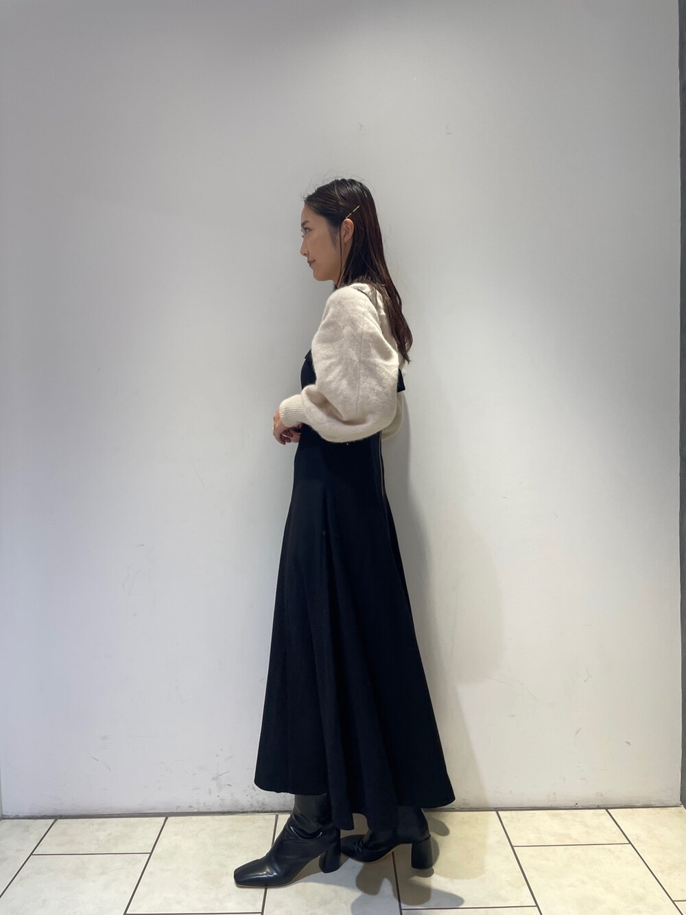 ホワイト系のニット/セーター、ブラック系のワンピース、ブラック系のブーツを着用したレディースの秋コーディネートの5枚目の写真