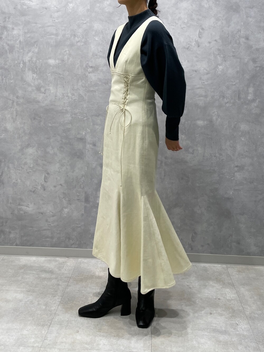 グリーン系のニット/セーター、ホワイト系のカーディガン/ボレロ、ブラック系のブーツを着用したレディースの冬コーディネートの6枚目の写真