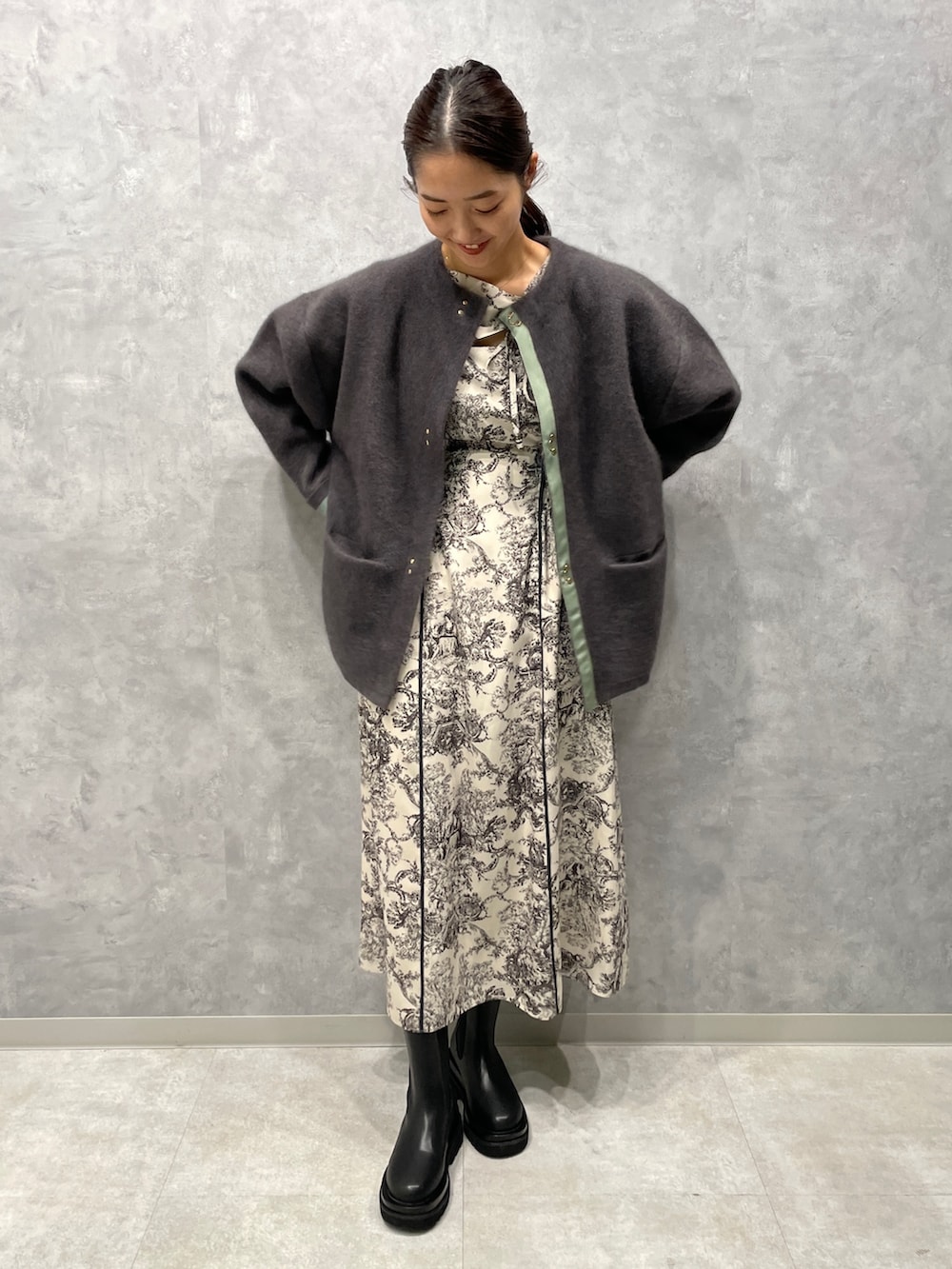 グレー系のカーディガン/ボレロ、ホワイト系のワンピース、ブラック系のブーツを着用したレディースの冬コーディネートの2枚目の写真