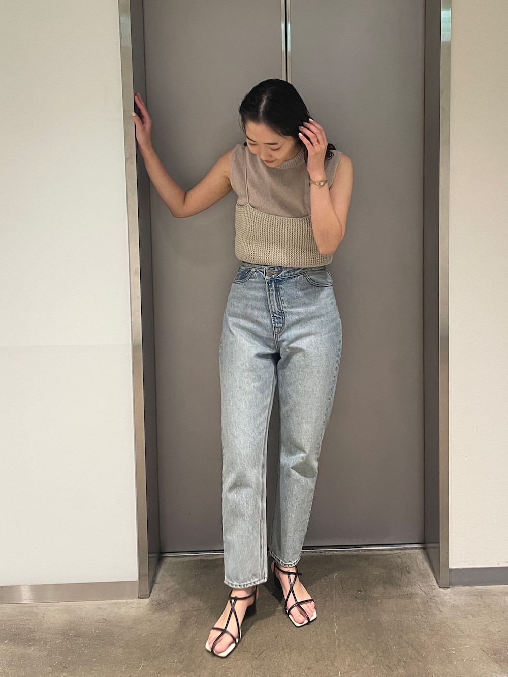 ブルー系のデニムパンツ、ベージュ系のニット/セーター、ブラック系のサンダルを着用したレディースの春コーディネートの3枚目の写真