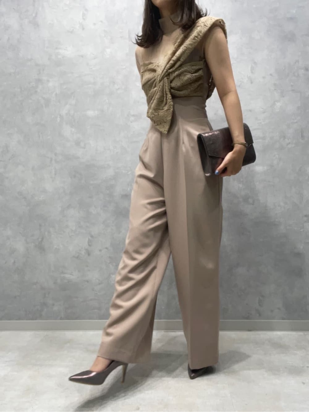 シルバー系のパンプス、シルバー系のクラッチバッグ、ベージュ系のパンツドレスを着用したレディースの夏コーディネートの6枚目の写真