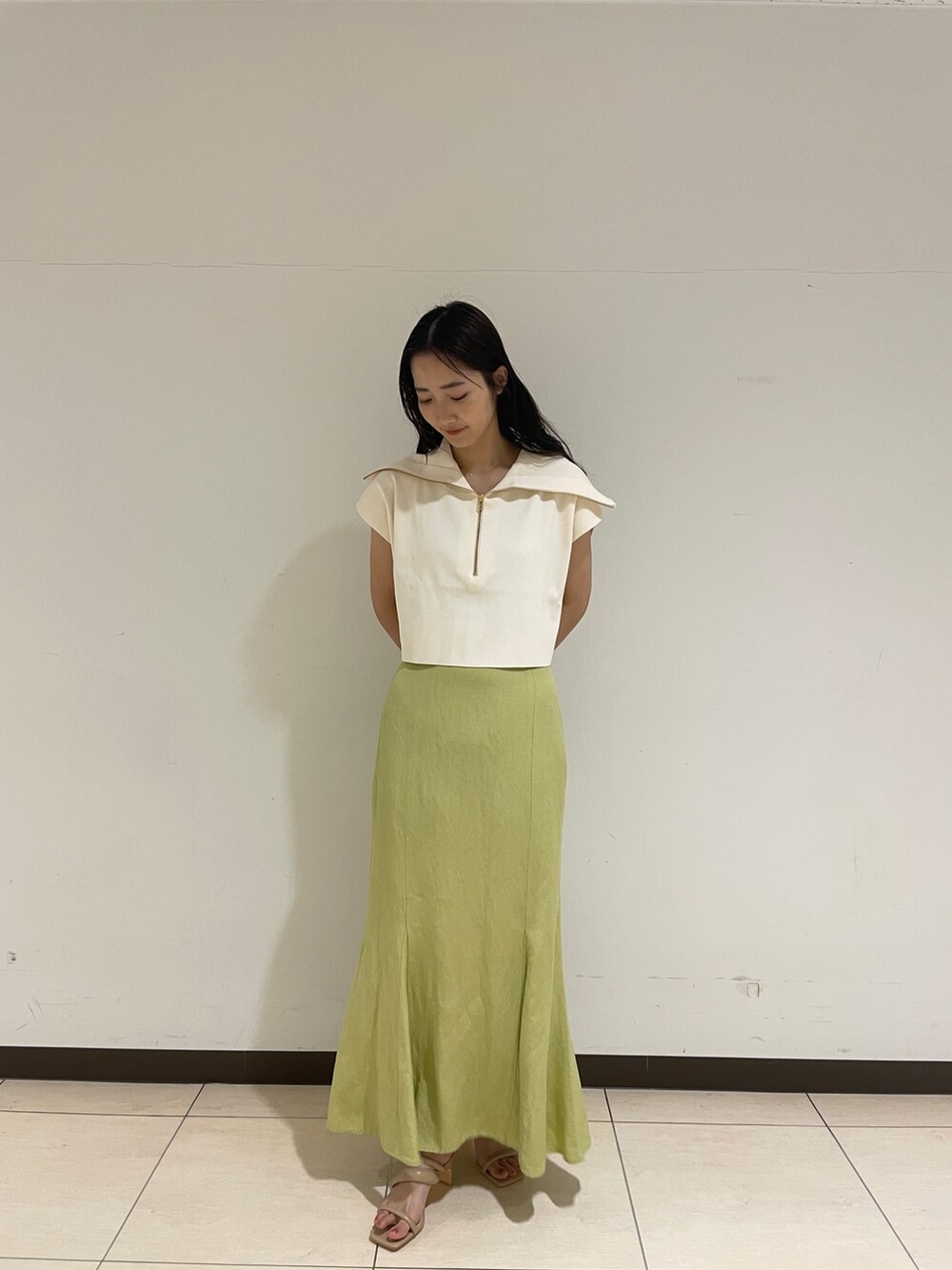 ホワイト系のニット/セーター、ベージュ系のサンダル、グリーン系のスカートを着用したレディースの春コーディネートの2枚目の写真