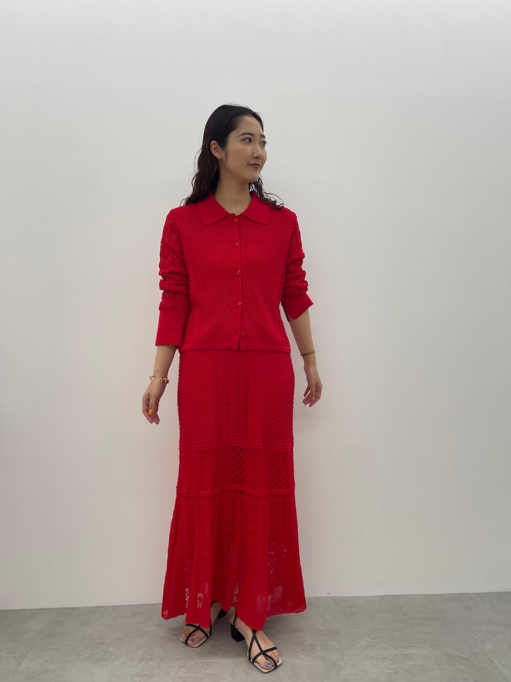 レッド系のカーディガン/ボレロ、レッド系のスカート、ブラック系のサンダルを着用したレディースの春コーディネートの4枚目の写真