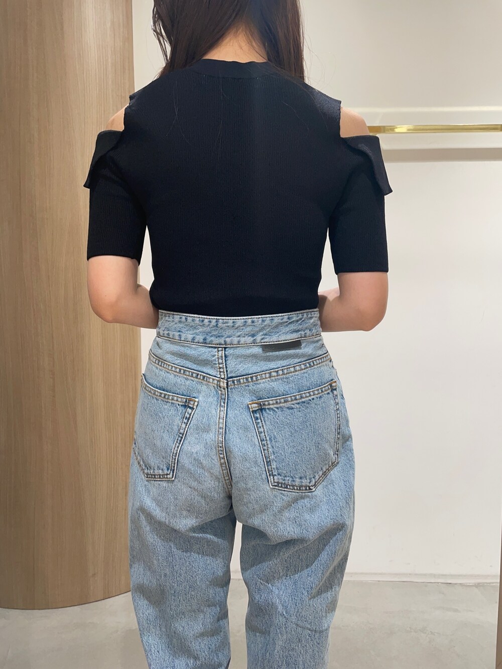 ブラック系のニット/セーター、ブラック系のサンダル、ブルー系のデニムパンツを着用したレディースの春コーディネートの7枚目の写真