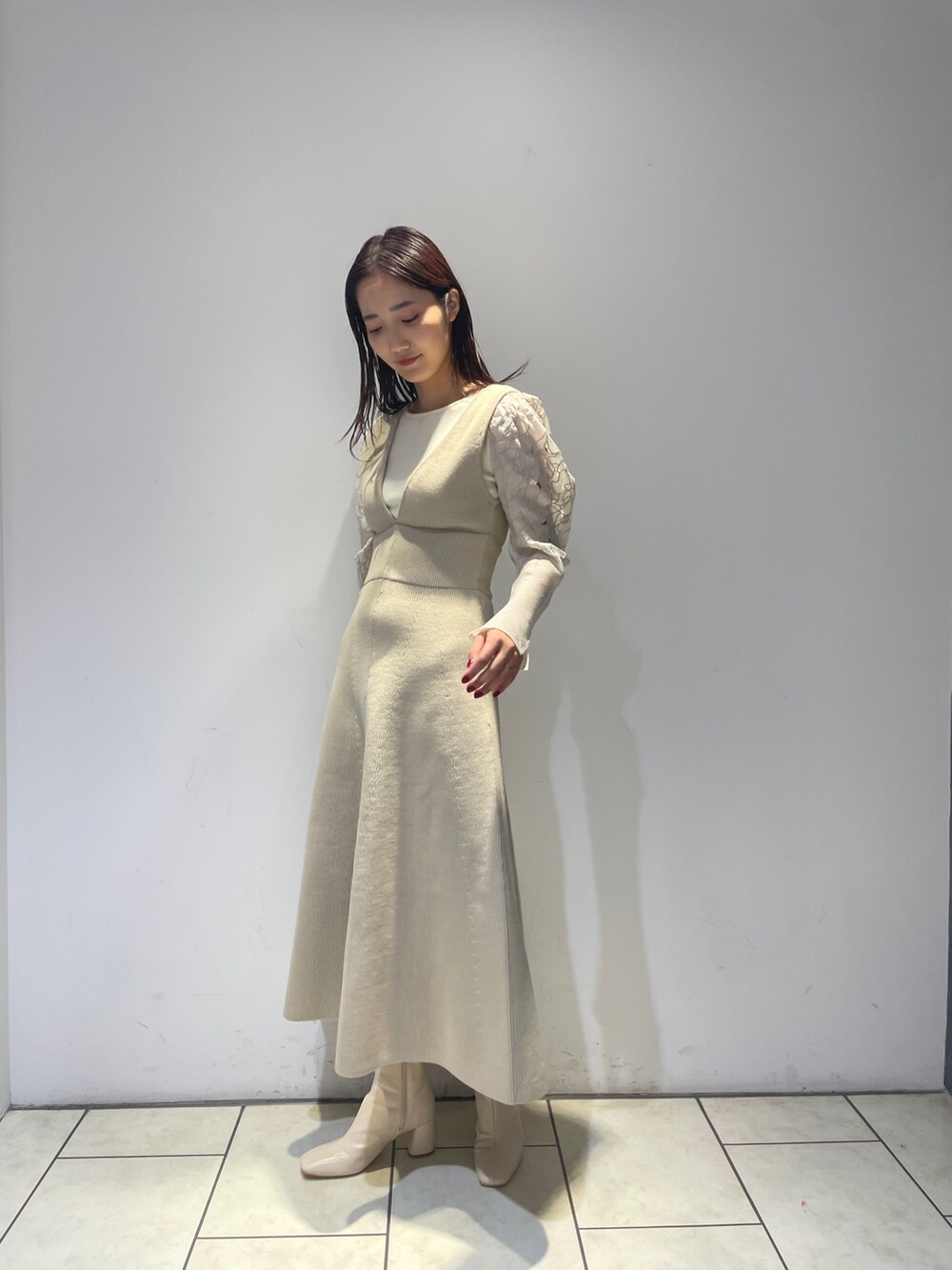 ホワイト系のニット/セーター、ホワイト系のジャンパースカート、ホワイト系のブーツを着用したレディースの秋コーディネートの3枚目の写真