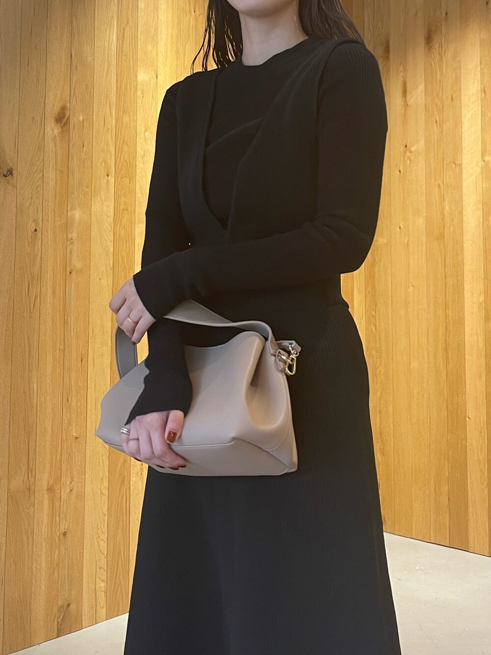 ベージュ系のハンドバッグ、グリーン系のブーツ、ブラック系のスカートを着用したレディースの秋コーディネートの6枚目の写真