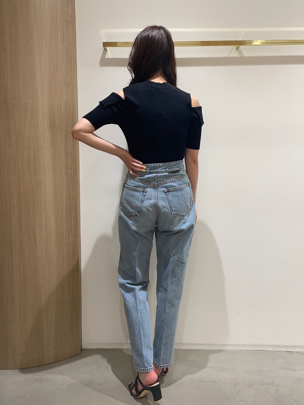 ブラック系のニット/セーター、ブラック系のサンダル、ブルー系のデニムパンツを着用したレディースの春コーディネートの5枚目の写真