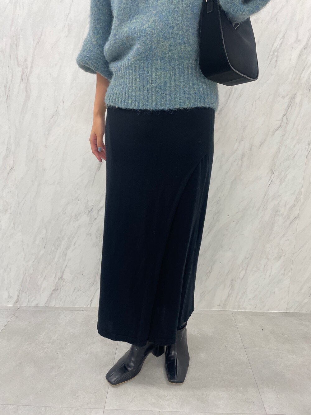 グリーン系のニット/セーター、ブラック系のブーツ、ブラック系のスカートを着用したレディースの冬コーディネートの8枚目の写真