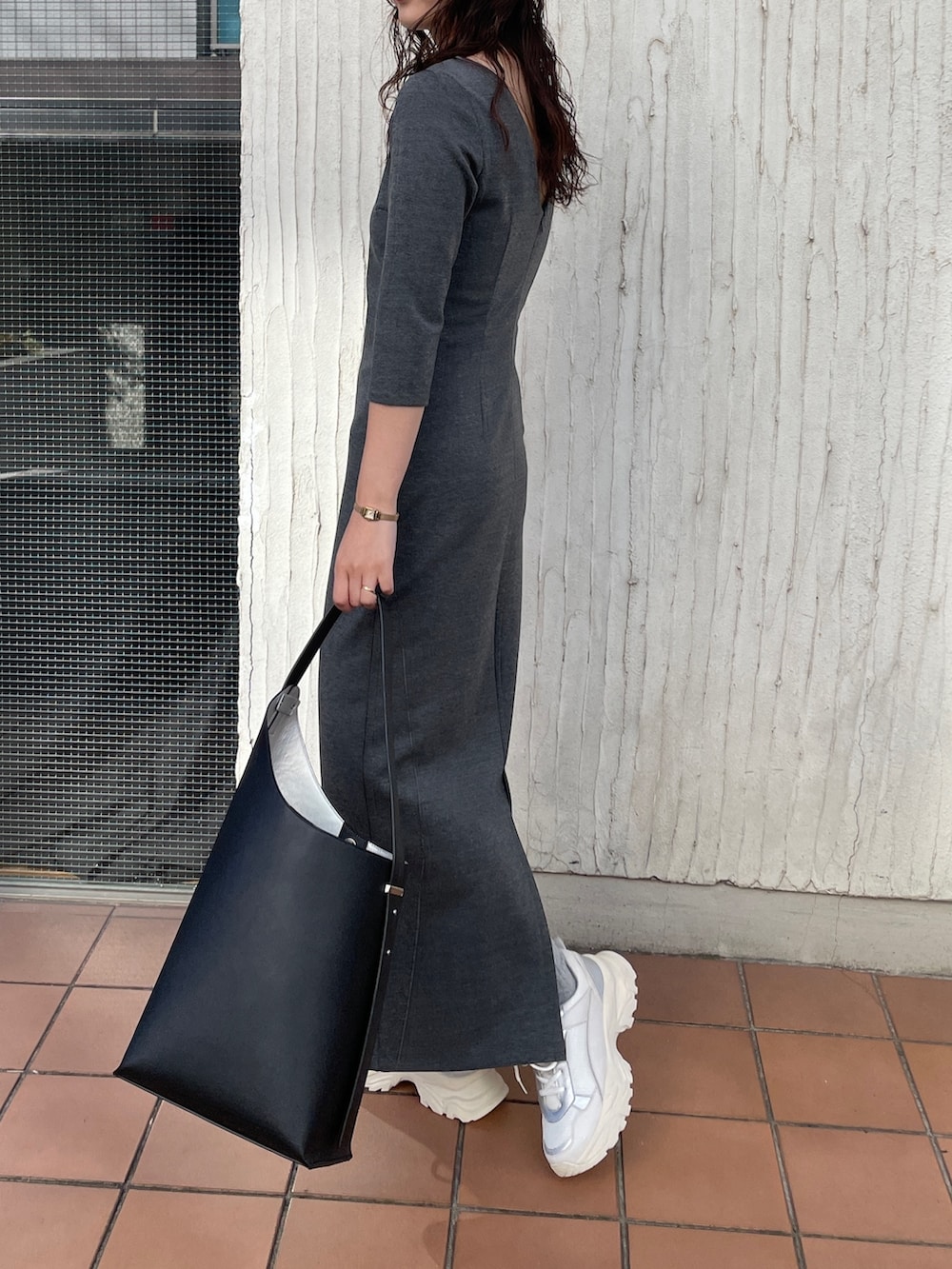 ブラック系のショルダーバッグ、グレー系のワンピース、ホワイト系のスニーカーを着用したレディースの冬コーディネートの5枚目の写真